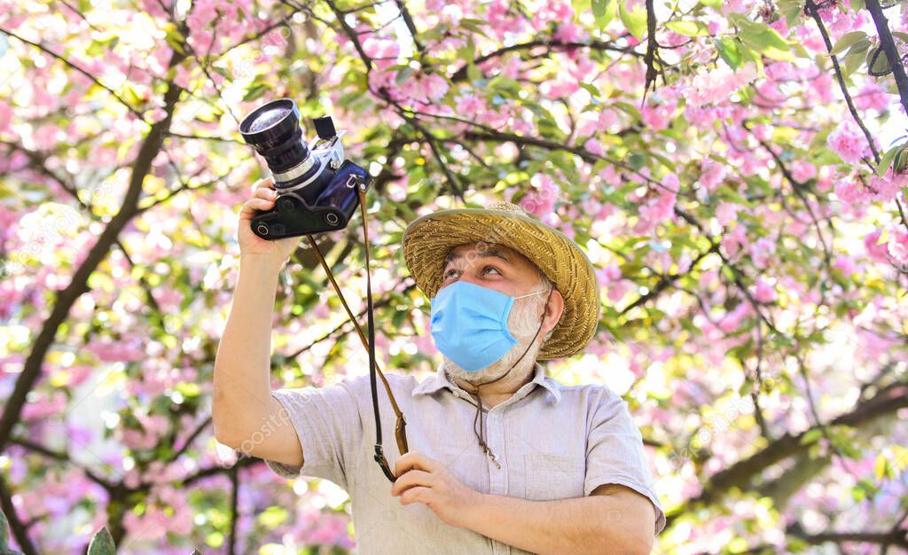 Tourist camera photo. Nature photography. Senior man respirator mask. Professional photographer work during coronavirus quarantine. Pandemic concept. Risky photographer. Keep working. Pollen allergy