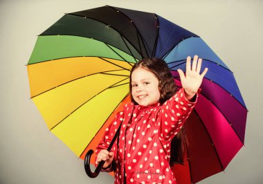 Sonbahar modası. Yağmur koruması. Gökkuşağı. Neşeli hippi çocuk pozitif ruh halinde. Renkli şemsiyeli mutlu küçük kız. Yağmurluk giymiş küçük bir kız. Kaygısız ve mutlu