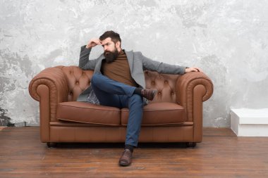 Sakallı hippi. Ciddi hippi koltukta rahatlar. Hippi sakallı bir iş adamı. Berber dükkanı ya da berber. Hippi moda trendi. İş gündelik tarzı. Erkek giyim mağazası