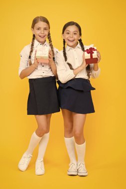 Büyük alışveriş günü. Mutlu kızlar sarı arka planda satışta hediyeler alıyor. Renkli kağıtlarla gülümseyen çocuklar okul üniforması giymiş kutular sunar. Tatil alışverişi konsepti