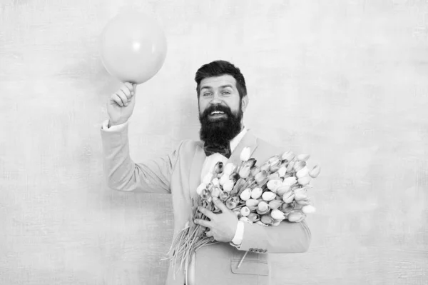 Arte do encanto. Um hipster feliz sai num encontro. Homem barbudo segura tulipas e balão. Perfeito primeiro encontro flores. Presente floral para data cromática. Dia dos Namorados. Lindas flores para impressionar com na data — Fotografia de Stock