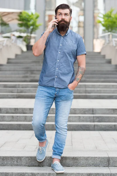 Conversation décontractée. Hipster dans un style décontracté urbain extérieur. L'homme barbu parle sur son portable. Tendances décontractées de la mode. Mode et style. Vêtements quotidiens. Décontracté magasin de vêtements pour hommes. La vie moderne — Photo