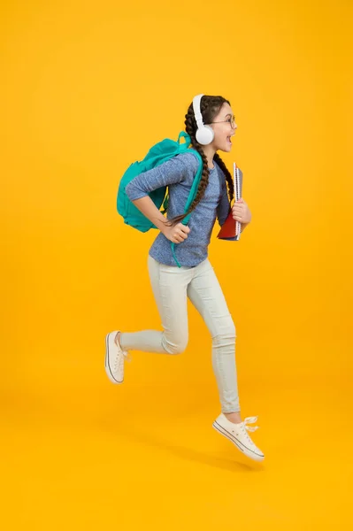 Lleno de energía. Un niño enérgico corre a la escuela. Chica feliz en movimiento fondo amarillo. Energía infantil. Mantener la energía cinética. Escuela y educación. Aprendiendo activamente. Estar en energía positiva — Foto de Stock