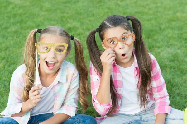 Parece chique. As meninas da festa usam óculos de adereço na grama verde. Amigos brincalhões. Feliz infância. Moda e beleza. Acessórios de moda de carnaval. Moda de verão. Estilo de moda. Accessorize seu olhar — Fotografia de Stock