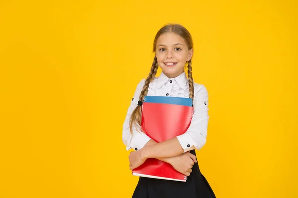 Cursussen voor begaafde kinderen. Basisniveau. Gelukkig schoolmeisje houden schoolboeken gele achtergrond. Klein schoolmeisje terug naar school. Kleine schoolmeisjes dragen een uniform. Schattig schoolmeisje. Schoolonderwijs — Stockfoto