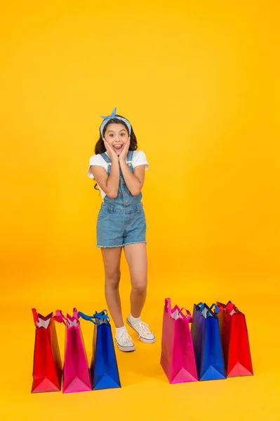 Niña con paquetes de compras. Niño feliz con bolsas. Niño pequeño en estilo veraniego. Ventas estacionales. Felicidad de compra. Día de compras. Boutique de moda. Chica alegre de compras. Tienda de cosméticos —  Fotos de Stock