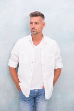 Olgun bir adam günlük kıyafetler giyer. berber saç bakımı. Seksi yetişkin adam. Tıraşsız yüzlü yakışıklı bir adam. Kendine güvenen adam dışarıda rahat duruyor. Karizma yayıyor. Erkek güzelliği ve moda