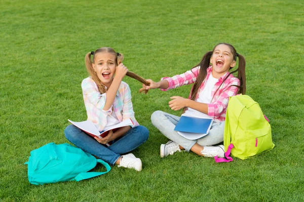 Mobbing in der Schule. Freizeit nach der Schule verbringen. Kleine Kinderfreunde entspannen sich im Gras. zurück zur Schule. Literatur für Mädchen. Hausaufgaben gemeinsam machen. finden Sie etwas interessantes in Buch. Notizen machen — Stockfoto