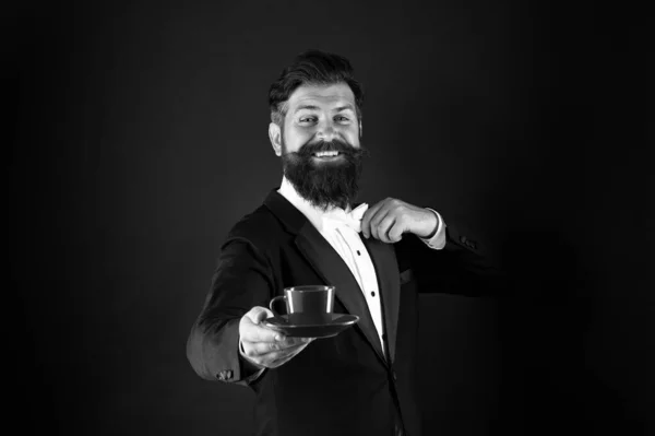 Çay servisi sanatı. Mutlu garson siyah çay servisi yapar. Sakallı adam bir fincan çay ver. Kahvaltılık çay. Sıcak içecek. Sabah içeceği. — Stok fotoğraf