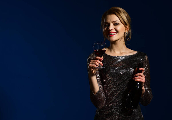 Lady in shining dress with smiling face drinks cabernet