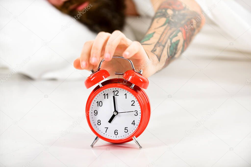 Male hand with tattoo try to turn off annoying alarm