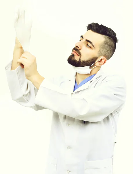 Cirujano con barba se pone guante con cara seria —  Fotos de Stock