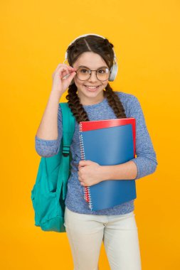 Ses kütüphanesi. Mutlu çocuk kütüphane kitaplarını tutuyor. Küçük kız kütüphaneye gidiyor. Okul kütüphanesi. Kitap ve edebiyat. Bilgi toplama günü. Bibliopol. Eğitim. Ses dili kursu. Dinliyor ve konuşuyor.