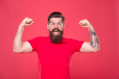 Her zaman güçlü ol. Güçlü hippi kollarını esnetiyor, kırmızı arka plan. Sakallı adam fiziksel güç gösteriyor. Güçlü pazılar ve trisepsler yapıyorlar. Güçlü kas egzersizi. Güç ve güç. Kendine inan.