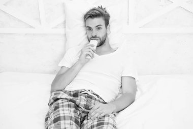 Uzaktan kumandalı pijamalı yakışıklı bir adam. Adam yatak odasında televizyon izliyor. Tembel pazar günü evde. Sabah programını izle. Adam televizyon izliyor. Yatakta uzaktan kumandayla kanal değiştir. Evde yatakta dinleniyor.