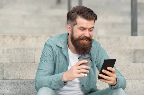 Tengo SMS en línea. El hombre feliz lee SMS bebiendo café al aire libre. Envío y recepción de SMS vía smartphone. Comunicación móvil. Mensajería SMS. Servicio de mensajes cortos. Nueva tecnología. La vida moderna. 3G. 4G — Foto de Stock