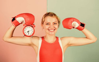 Its time for boxing training. happy woman boxing gloves. girl boxer hold alarm clock. morning energy. full of power. activity time. Establishing the clock time. time to fight. win the day