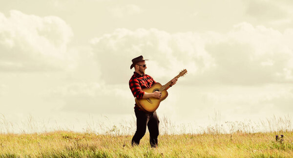 music begins. sexy man with guitar in checkered shirt. western camping and hiking. hipster fashion. happy and free. cowboy man with acoustic guitar player. country music song