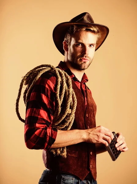 Bebe um copo. rodeio oeste selvagem. Um homem de chapéu bebe uísque. Camisa xadrez no rancho. cowboy com corda de laço. Ocidental. Homem de estilo vintage. cowboy retro do Oeste Selvagem. cowboy ocidental retrato — Fotografia de Stock