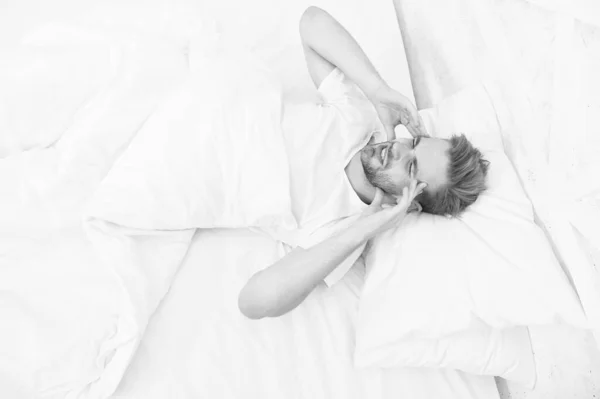Ημικρανίες. Όμορφος άντρας χαλαρώνει στο κρεβάτι. Το ροχαλητό μπορεί να αυξήσει τους πονοκεφάλους. Κοινό σύμπτωμα άπνοιας στον ύπνο. Αιτίες πρωινού πονοκεφάλου. Προβλήματα ύπνου μπορεί να οδηγήσει σε πονοκεφάλους το πρωί — Φωτογραφία Αρχείου