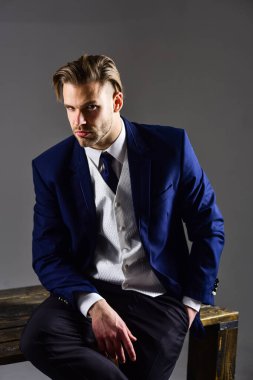 Klasik takım elbiseli ciddi bir adamın karanlık stüdyo portresi.