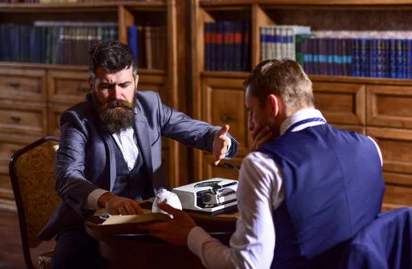 Man with beard interviews writer. Man in suit or journalist