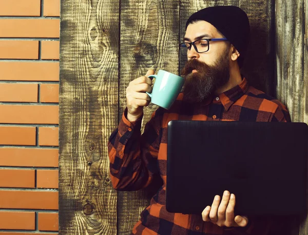 Barbudo brutal caucásico hipster celebración portátil con taza —  Fotos de Stock