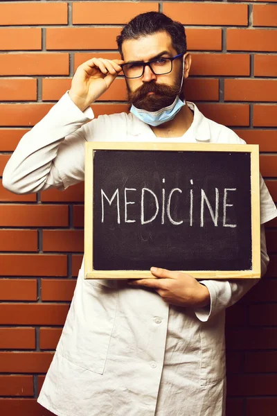 Barbudo brutal caucasiano médico segurando bordo com medicina inscrição — Fotografia de Stock