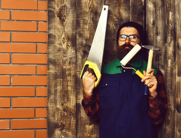 Бородатий художник тримає різні будівельні інструменти з серйозним обличчям — стокове фото