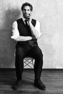 Ciddi bir moda işçisi sandalyede oturuyor.