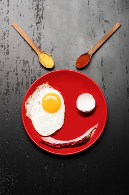 Baharatlı ve biberli kaşıkların yanında kızarmış yumurtalı tabak.