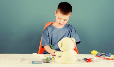 Çocuk doktoru stajyeri. Tıp üniformalı küçük bir çocuk. Steteskoplu çocuk doktoru. Hastane. İlaç ve sağlık. Tedavi reçetesi. Hemşire laboratuvar asistanı. Aile doktoru. oyuncakla oynamak
