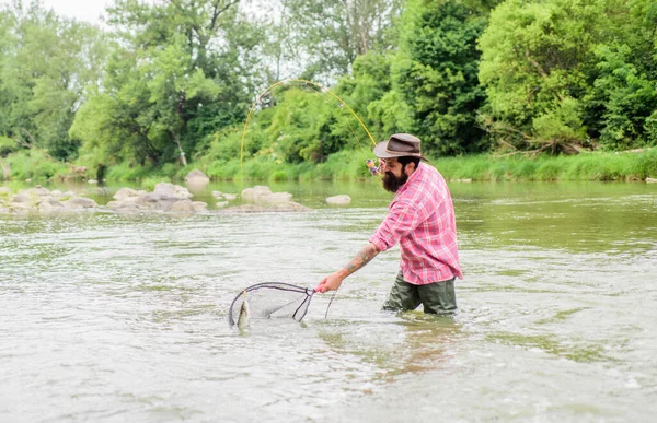 Hobby di pesca. Barbuto brutale pescatore cattura pesce trota con rete. Se il pesce regolarmente si sa come la pesca gratificante e rilassante è. La pesca è uno sport all'aperto ricreativo accessibile sorprendente — Foto Stock