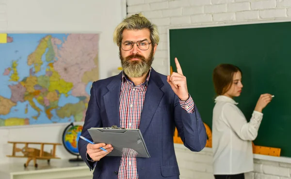 Śledź postępy studentów. Nauczyciel sprawdza prawidłową odpowiedź. Nauczanie z pasją. Materiały edukacyjne. Którego dzisiaj nie ma. Mała dziewczynka przy tablicy. Wracać do szkoły. Uczeń i nauczyciel w klasie — Zdjęcie stockowe