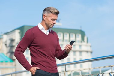 İş iletişimi. Çevrimiçi iletişim. Modern iletişim. İş adamı cep telefonunu tutar. Dışarıda telefonu olan yakışıklı bir adam. Taşınabilir yaşam tarzı. İnternet bağlantısı. Kullanışlı uygulama