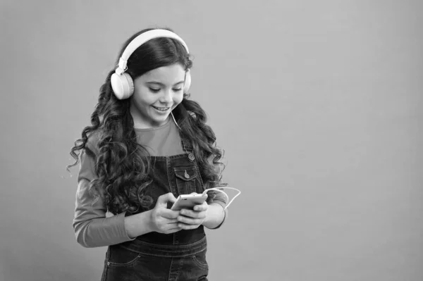 Entretenimiento online. Aplicaciones de música gratis. Escucha gratis. Obtener suscripción a una cuenta de música. Disfruta del concepto musical. Disfruta del sonido perfecto. Niña pequeña escuchar música auriculares modernos y teléfonos inteligentes — Foto de Stock