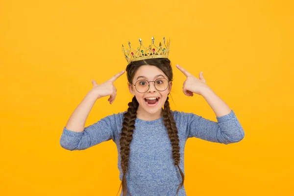 Think cool. Cool child point at crown on head. Happy beauty queen yellow background. Fashion accessories. Cool and trendy prom jewelry. Beauty salon. Cool from head to toe