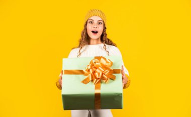 Sevgili Noel Baba. Sürpriz. Noel hediyesi kutusu olan mutlu küçük bir kız. Çocuk hediye kutusunu sarı arka planda tutuyor. Mutlu Noeller ve yeni yıl. Elimde Noel hediyesi var. Noel konsepti