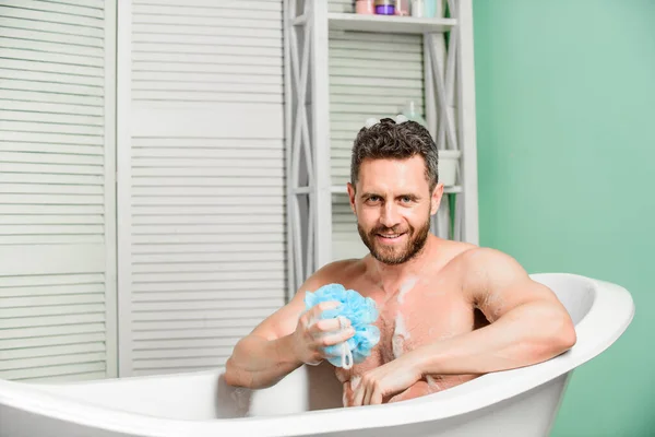 macho man washing in bath. desire and temptation. man wash muscular body with foam sponge. personal care. Sexy man in bathroom. hygiene and health. Morning shower. Male body with sexy strong torso.