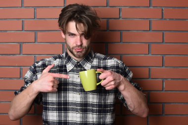 Duvarda fincanı tutan yakışıklı adam.