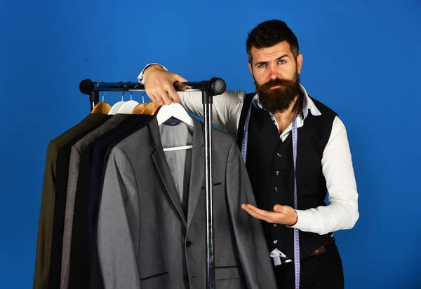 デザイナーは服のハンガーの近くにスーツを提示する。髭を生やした男 — ストック写真