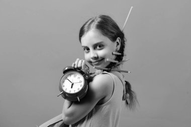 Çocuk renkli kalemler ile pembe elbiseli çalar saat tutar