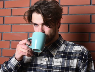 Duvarda fincanı tutan yakışıklı adam.