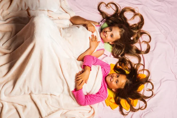 Schoolgirls have pajama party. Kids in pink pajamas under blanket — Stock Photo, Image