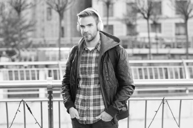 Modern tarzda. Yakışıklı adam şehir dışında kulaklık takıyor. Genç adam modern müzik dinler. Modern müzik teknolojisi. Çağdaş müzik. Yeni teknoloji. Modern hayat