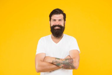 Sarı arka planda mutlu vahşi sakallı adam. Yakışıklı, kendine güvenen bir adamın mükemmel bir saç stili var. Erkek yüz bakımı. Vahşi sakallı adamın portresi. Düşünen şık adam gülümsüyor.