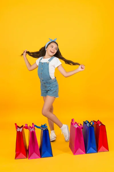 Obchod s kosmetikou. Holčička s nákupními balíčky. Šťastné dítě v obchodě s taškami. Malé dítě v letním stylu. Sezónní prodej. Zboží na vlasy. Nákupní den. Módní butik. Veselá dívka nakupování — Stock fotografie