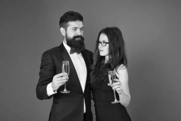 Proost op Valentijnsdag. Een paar verliefd op een rode achtergrond. Sexy vrouw en bebaarde man met champagneglazen. Valentijnsdag. Feestje voor Valentijnsdag. Gelukkige Valentijnsdag — Stockfoto