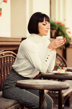 Çekici, zarif, esmer bir kadın tatlı ve kahve kafesi terası arka planının tadını çıkarıyor. Keyifli zaman ve rahatlama. Lezzetli ve gurme atıştırmalıkları. Kahve ve tatlı ile kafeyi rahatlatan bir kız. Tatlı konsepti