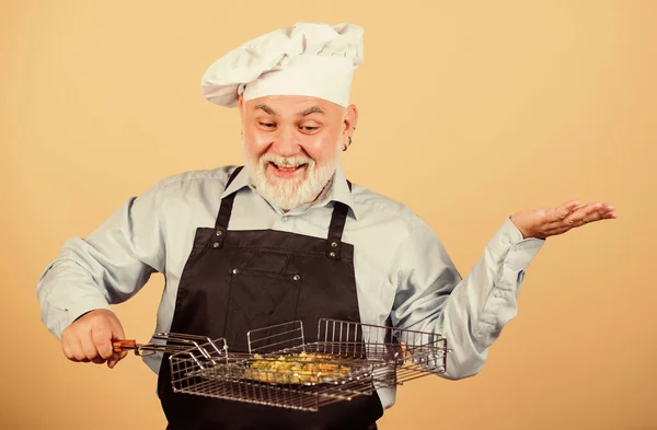 Gewoon voor de lol. Hij geeft de voorkeur aan grillvoedsel. Picknick en barbecue. Keukenregels. Maak het eten klaar voor familie. Familieweekend. Oudere man met koksmutsen. Kook mannen met een baard. kookgerei voor de barbecue — Stockfoto